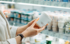 Close-up of a woman's hands holding a yoghurt pot while reading the label