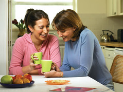 mother and daughter smiling drinking out of a mug