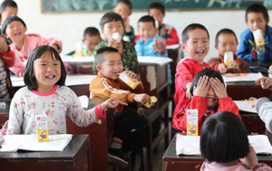 Classroom of Chinese students laughing with cartons of milk