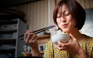 Woman eating from a bowl with chopsticks