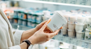 Close-up of a woman's hands holding a yoghurt pot while reading the label