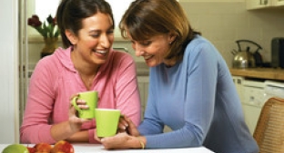 mother and daughter smiling drinking out of a mug
