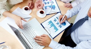 aerial view of man and woman working at a laptop with graphs on the table