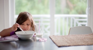Small child eating cereal at a table