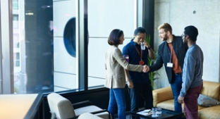 Business leaders shaking hands in front of glass window