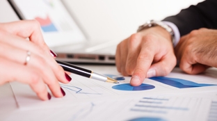 Hands pointing at graphs on paper Hands pointing at graphs on paper