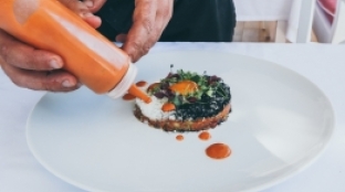 Adding a dressing to small plate of food dressing